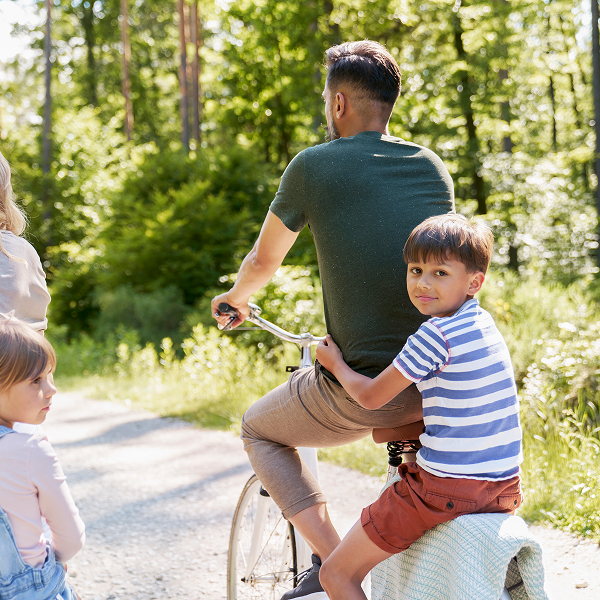 Un homme et une femme font du vélo avec deux enfants, illustrant des activités familiales en plein air.