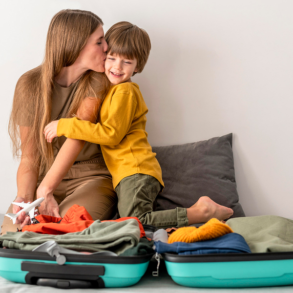A woman and a child sitting on suitcases, smiling, ready for their vacation adventure.